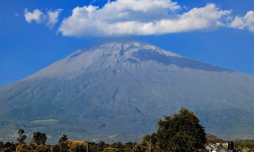 Scenic view of Mount Meru under a cloud with lush greenery, Arusha, Tanzania.